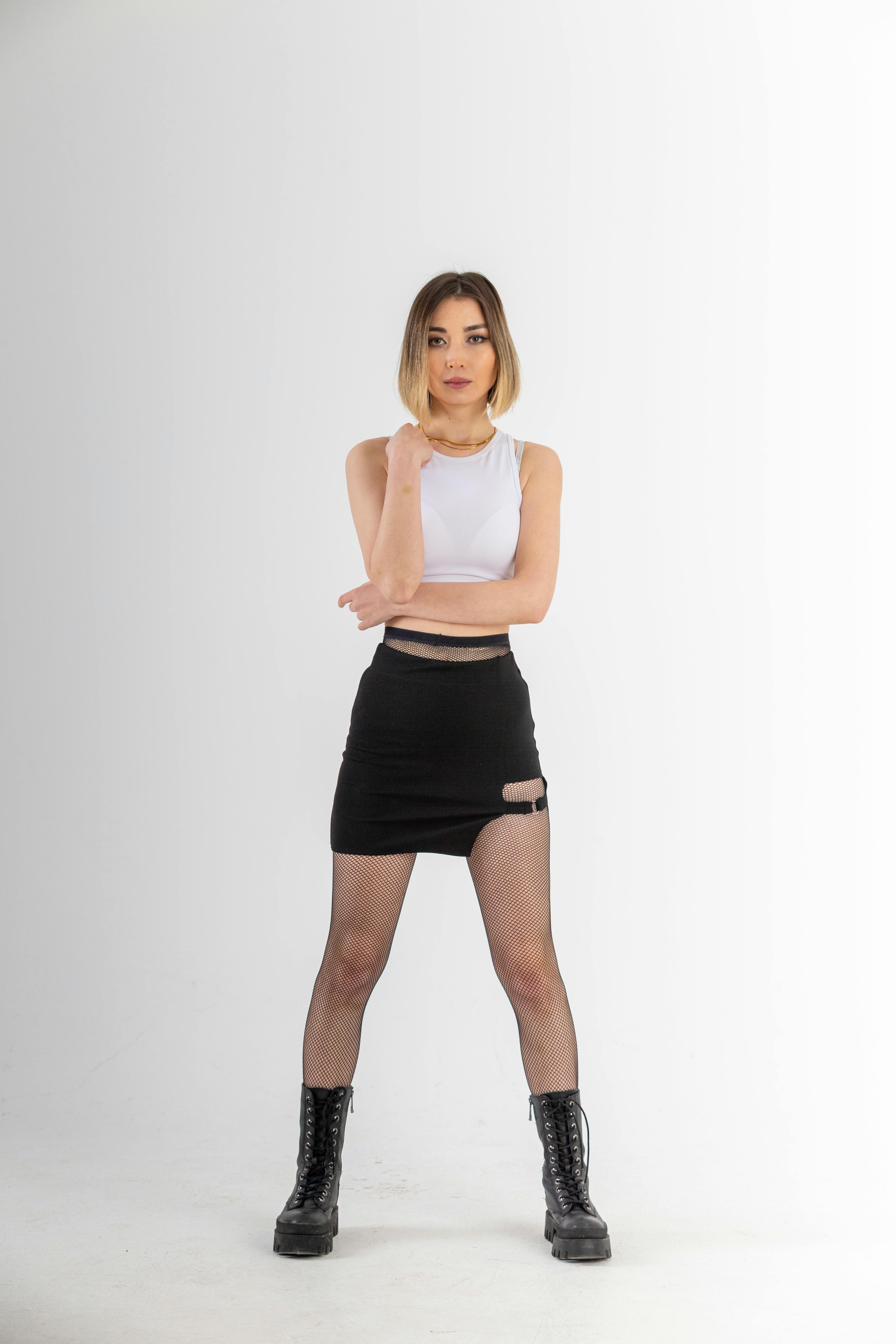 Free Confident model posing in a chic black skirt and boots, showcasing modern fashion. Stock Photo