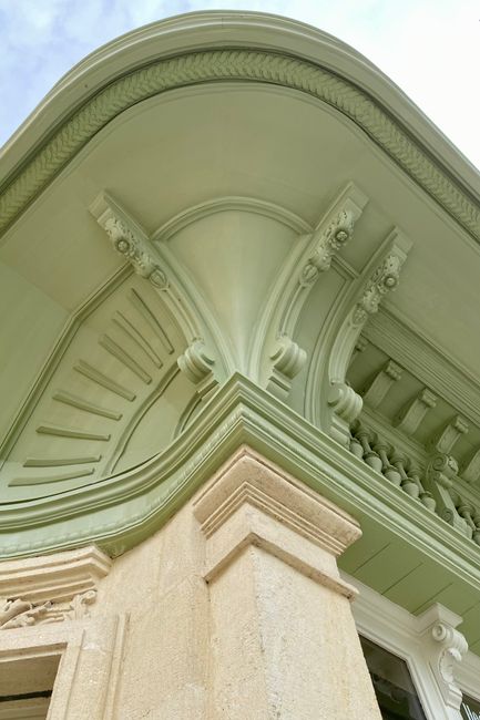 Close-up view of a classic architectural facade with intricate design elements and soft green tones.