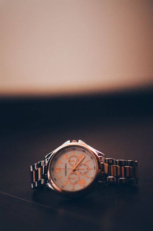 Free Close-up of an elegant gold-tone wristwatch with Roman numerals on a dark background. Stock Photo