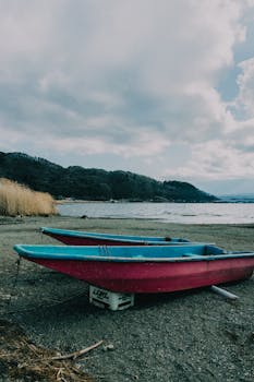 Two colorful boats on the shore of Kawaguchiko Lake, Japan, with a scenic mountain backdrop.