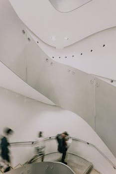 Blurred figures move on a winding staircase inside a Tokyo museum.