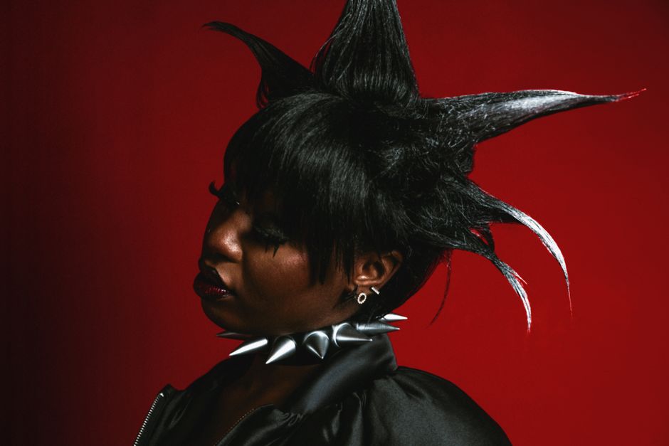 Portrait of a woman with spiky hair and spiked choker on a red background.