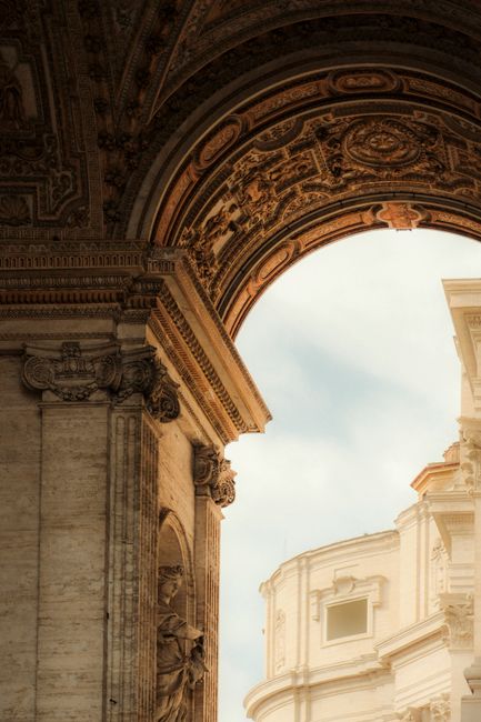 Close-up of a beautifully detailed architectural arch and building facade under a bright sky.