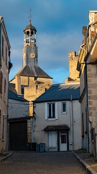 Quaint European street leading to historic clock tower under blue sky. — photo by Adrien  Gambet