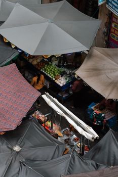 Aerial shot of a vibrant outdoor market with food stalls and umbrellas, capturing daily life.