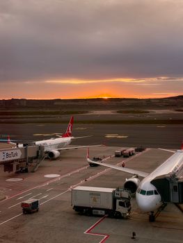 Scenic view of airplanes on an airport runway against a golden sunrise.