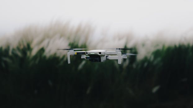 White drone flying over blurred grass background. Capturing technology in nature.