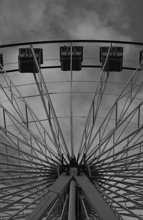 Free Monochrome Ferris wheel shot from below with cloudy sky backdrop, creating an artistic perspective. Stock Photo