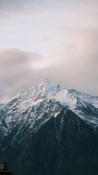 A stunning view of a majestic snow-capped mountain peak against a serene sky at dusk.