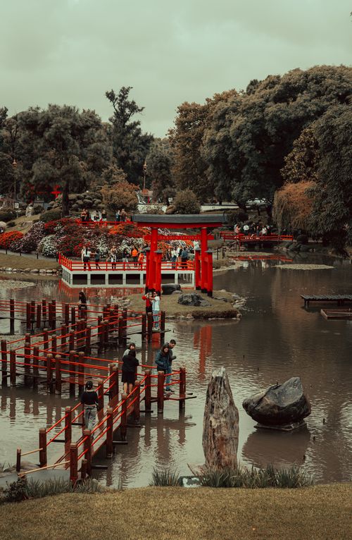 Free Beautiful Japanese garden scene featuring a red Torii gate, lush foliage, and tranquil water. Stock Photo