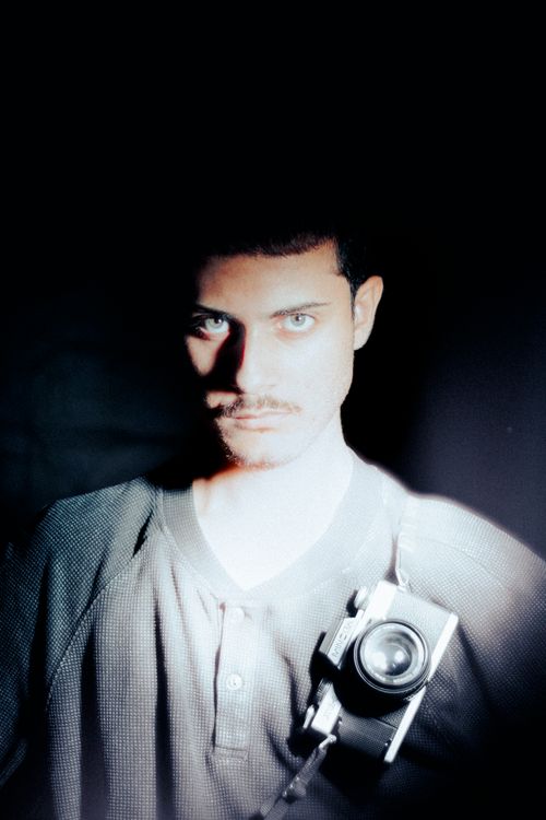 Free Moody portrait of a man holding a vintage camera in dark lighting. Stock Photo
