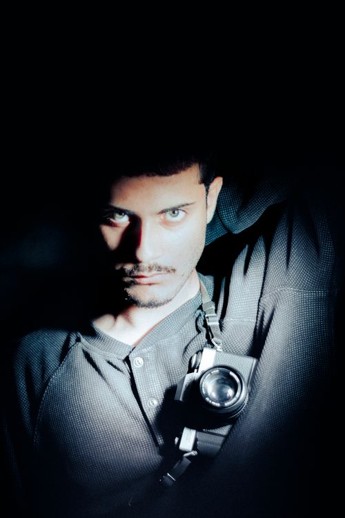 Free Intense portrait of a man holding a vintage camera, captured in moody lighting. Stock Photo