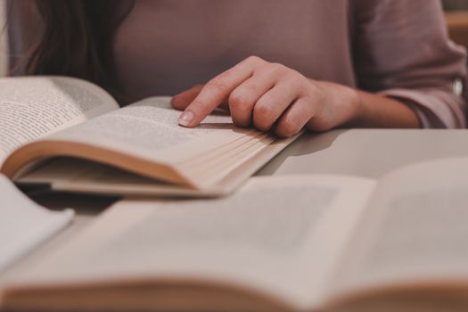 Close-up of a woman reading a book indoors, focusing on the turning of pages.