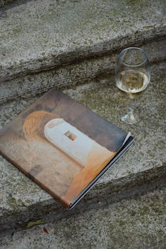 An art book and a wine glass on stone steps evoke a relaxed, artistic ambiance.