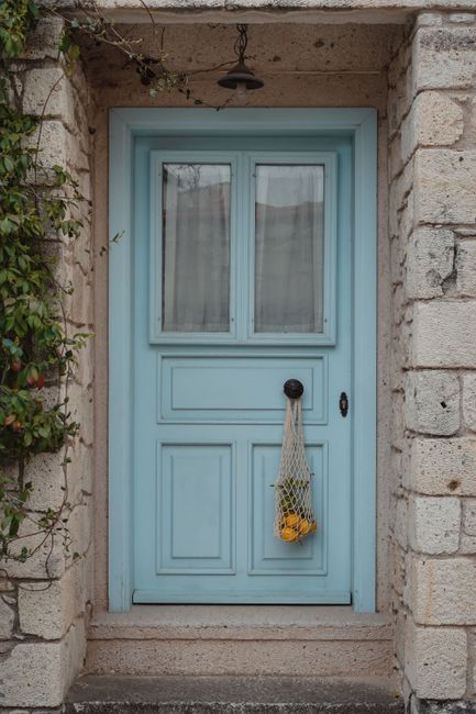 Rustic blue door with a hanging mesh bag of fruit, surrounded by ivy.
