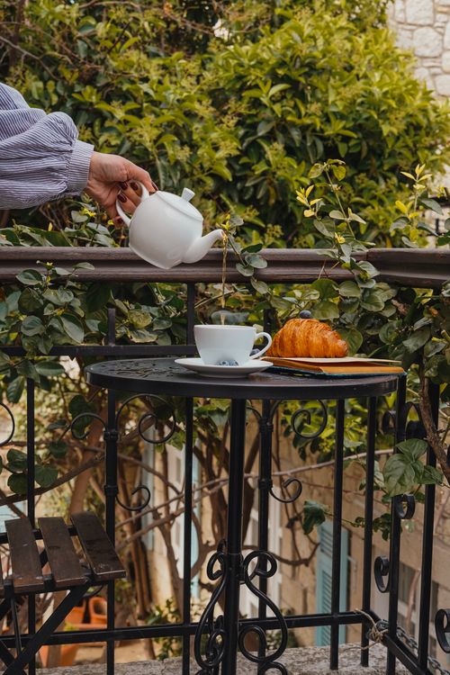 Free Elegant balcony breakfast setup with tea pouring and croissant. Stock Photo