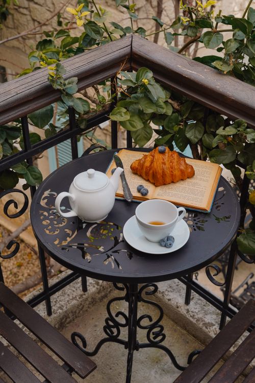 Free A cozy balcony breakfast scene with croissant, tea, and blueberries. Stock Photo