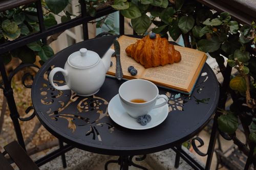 Free Serene breakfast on a balcony with tea and croissant. Perfectly cozy scene. Stock Photo