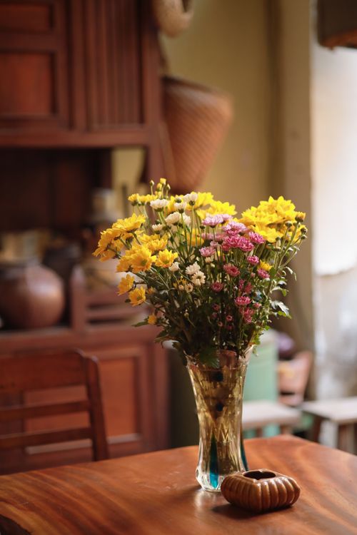 Free Elegant bouquet of flowers in a vase on a wooden table in a rustic interior. Stock Photo