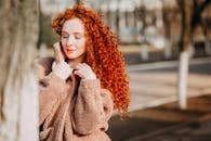 穿着蓬松外套的红发女子享受阳光明媚的秋日，展现出自然之美和充满活力的头发