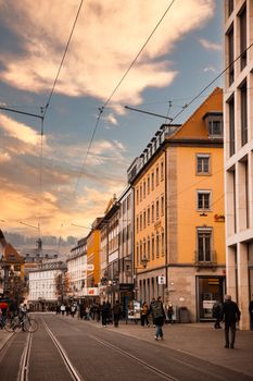Beautiful urban street scene with historic buildings and people at sunset.