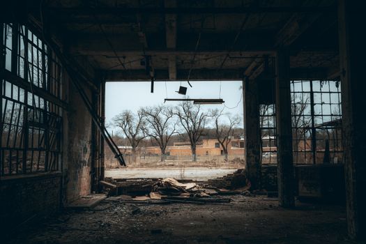 Atmospheric view from an abandoned building with broken windows and a moody sky.