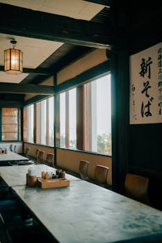 Cozy Japanese restaurant interior with wooden tables and traditional decor, illuminated by soft natural light.
