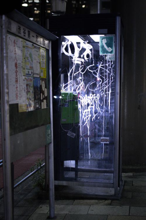 Free A graffiti-covered phone booth at night, creating a moody urban scene. Stock Photo