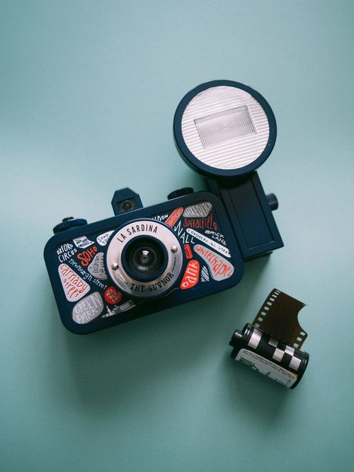 Free Colorful toy camera with an attached flash and a film roll, on a teal background. Stock Photo