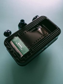 A vintage 35mm film reel inside a black lomography toy camera, top view.