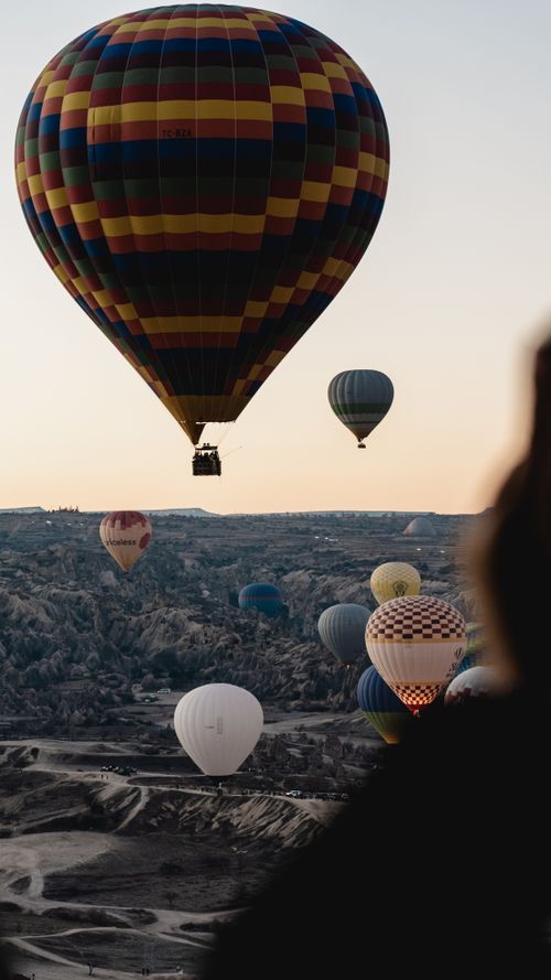 Free Colorful hot air balloons float over the rocky hills of Cappadocia during sunrise, creating a breathtaking scene. Stock Photo
