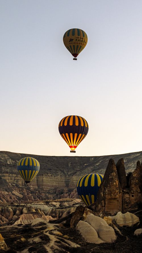 Free Colorful hot air balloons soar over Cappadocia's unique rock formations at dawn. Stock Photo