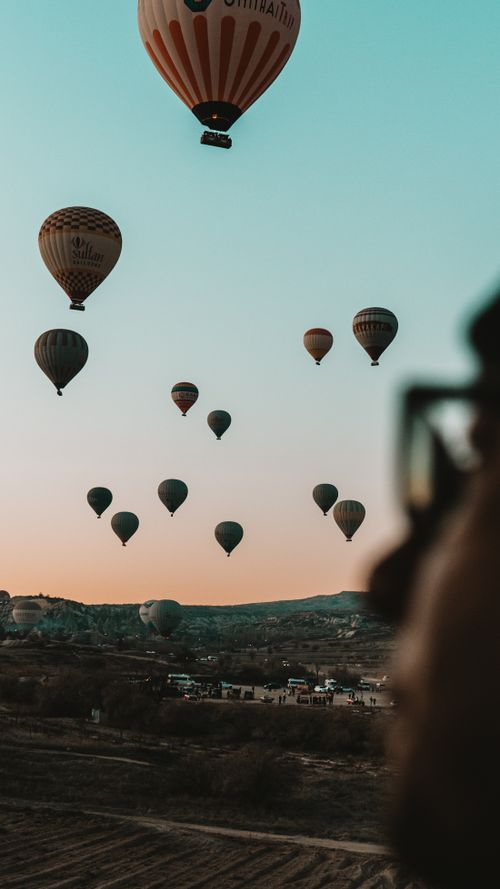 Free Colorful hot air balloons fill the sky at sunrise over Cappadocia's unique landscape. Stock Photo