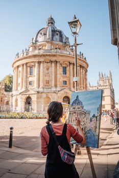 Woman painting the Radcliffe Camera in Oxford on a sunny day, capturing the iconic architecture.