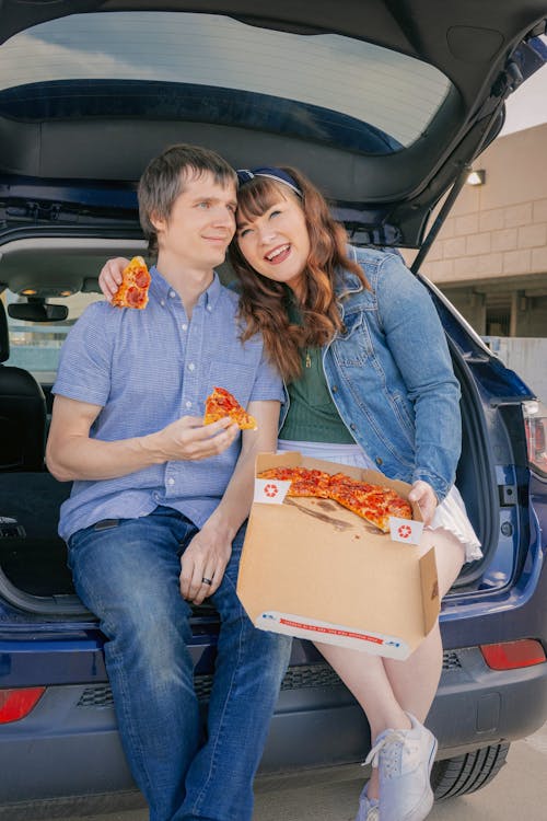 Free A joyful couple enjoying pepperoni pizza in the trunk of their car. Perfect for lifestyle images. Stock Photo