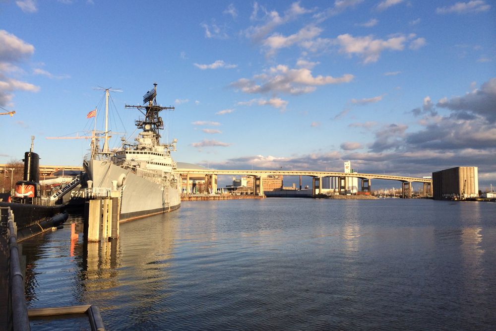 USS Little Rock docked at Buffalo waterfront, with city bridge skyline and serene waters.