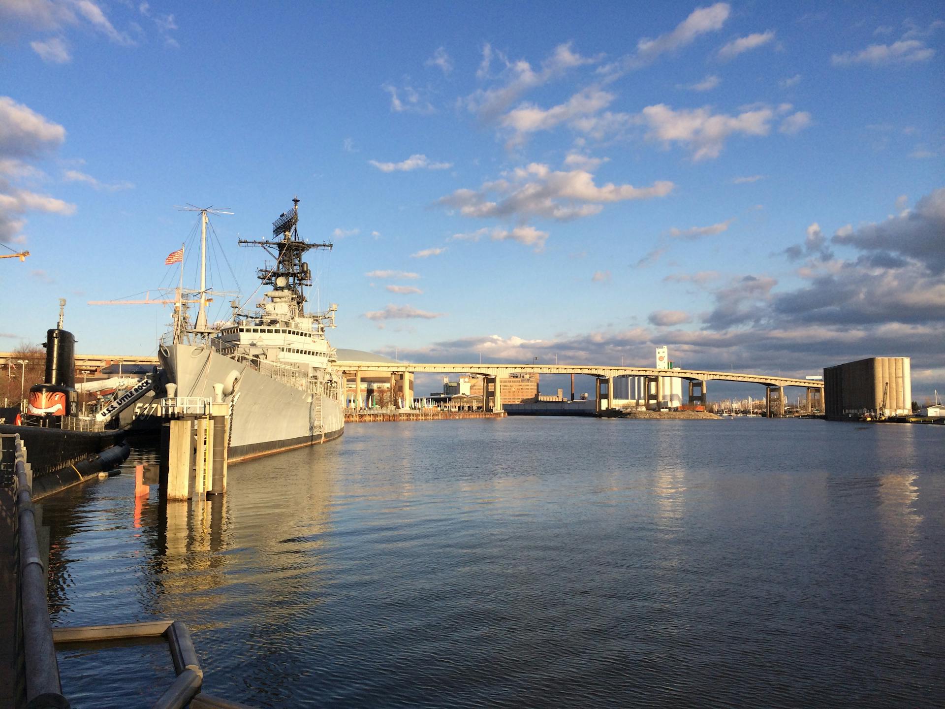 USS Little Rock docked at Buffalo waterfront, with city bridge skyline and serene waters.