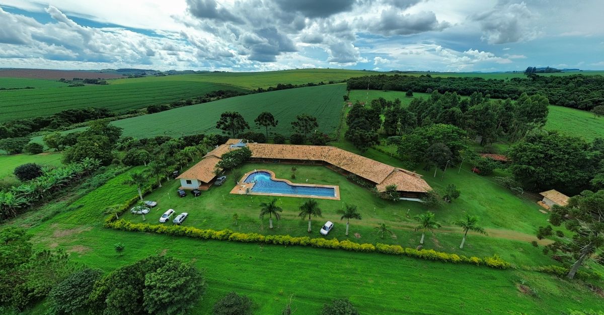 Aerial photo of a countryside estate with lush greenery and a large swimming pool surrounded by fields.