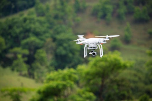 A white drone flying over a lush, green landscape, capturing stunning aerial views.
