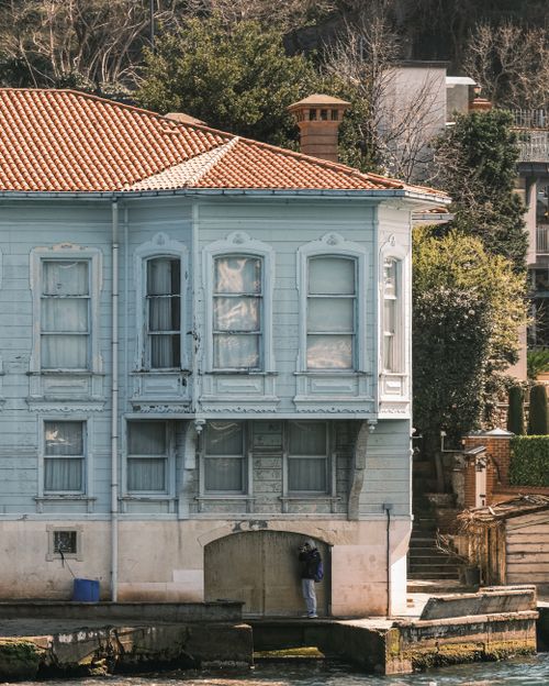 Free A serene blue waterfront house with classic architecture set against a lush backdrop, ideal for lifestyle themes. Stock Photo