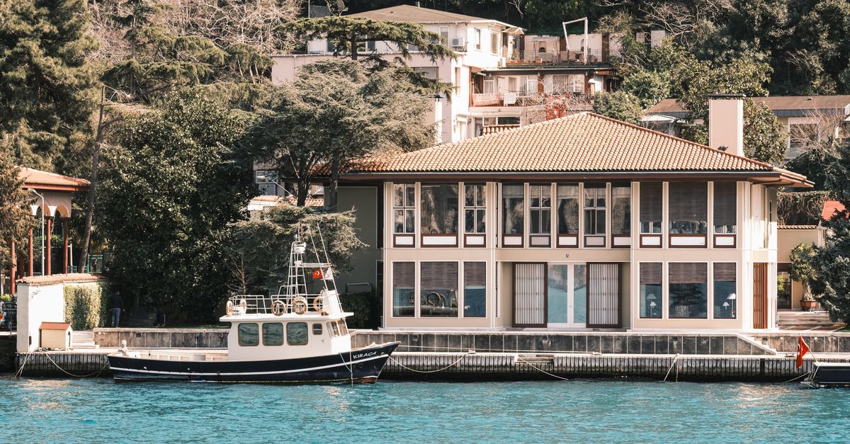 A scenic view of a waterfront house with a boat docked by the tranquil waters.