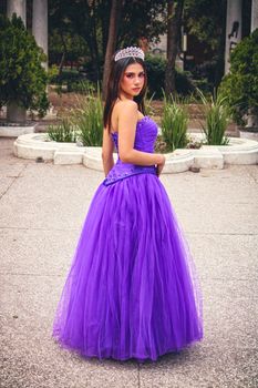 Woman in a vibrant purple gown posing in an outdoor park setting.