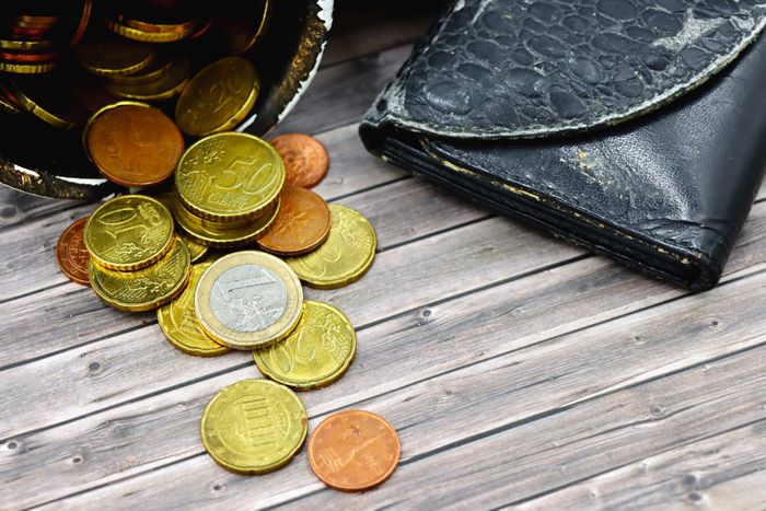 A worn leather wallet with scattered coins — photo by Marta Branco on Pexels
