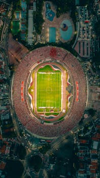 A vibrant aerial shot of a crowded stadium at night with a brightly lit football field.