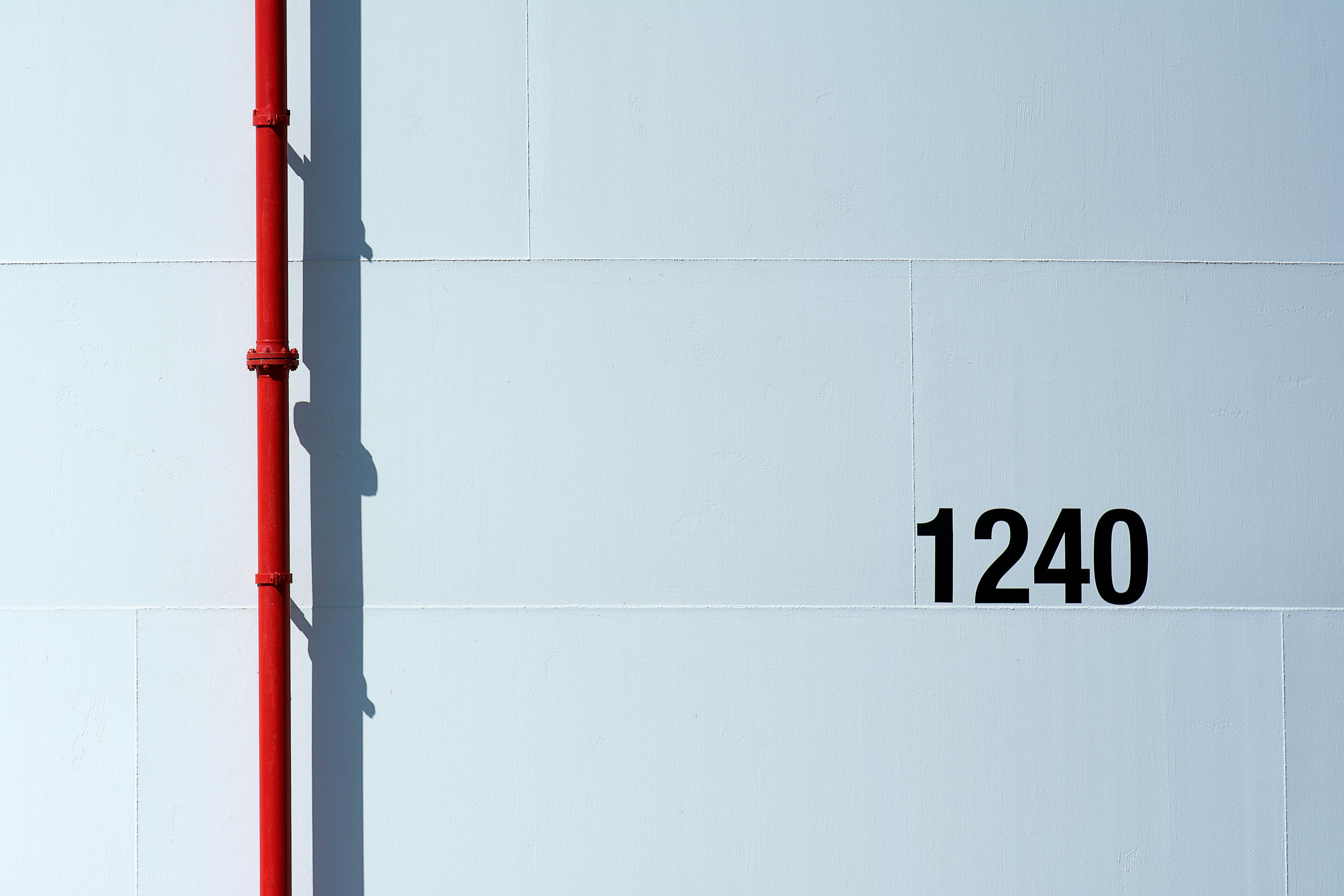 Ücretsiz Beyaz bir duvarın önünde kırmızı bir pipo ve 1240 numaralı bir tablonun yer aldığı minimalist bir kompozisyon. Stok Fotoğraflar