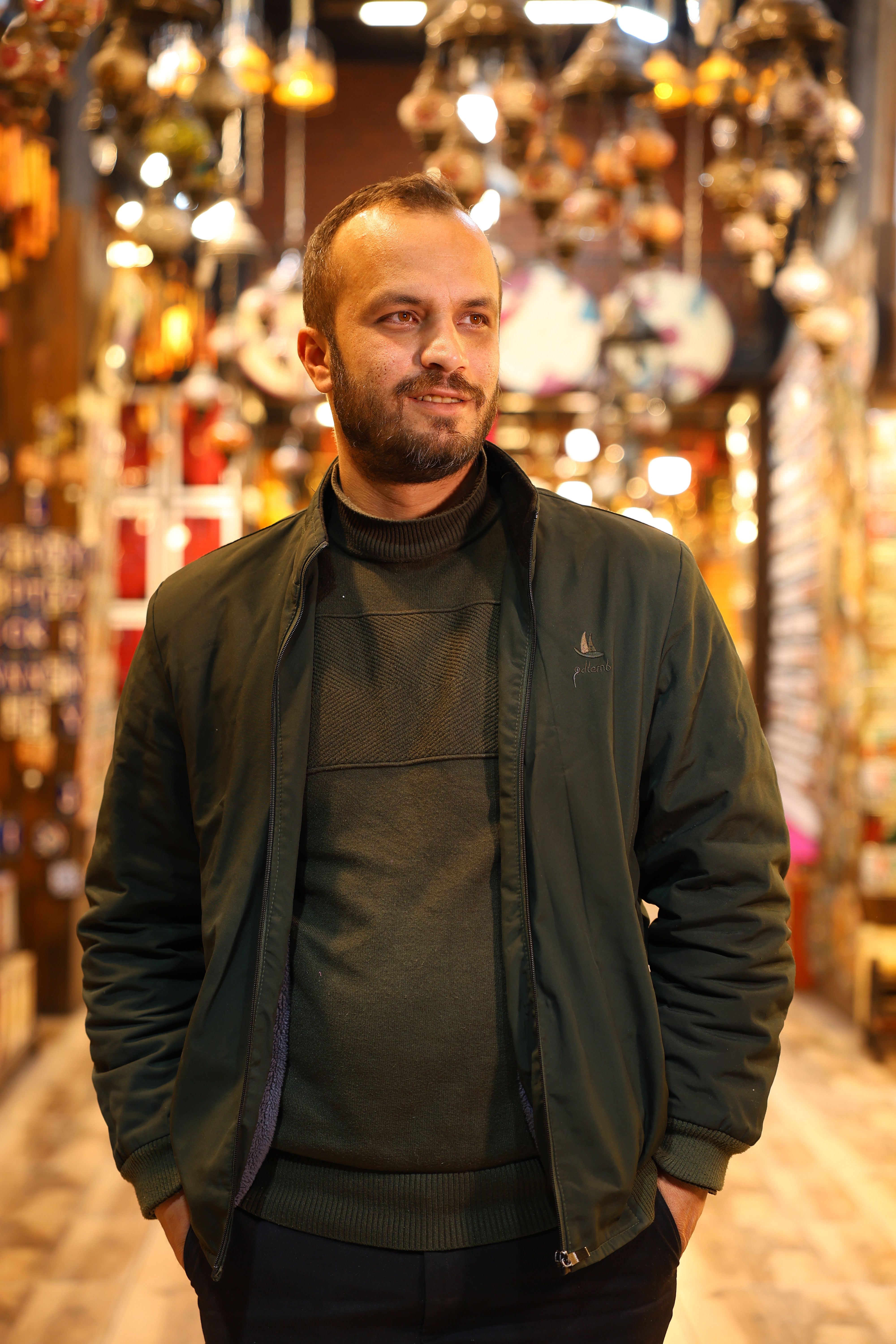 Smiling man in lantern shop with colorful hanging lamps.