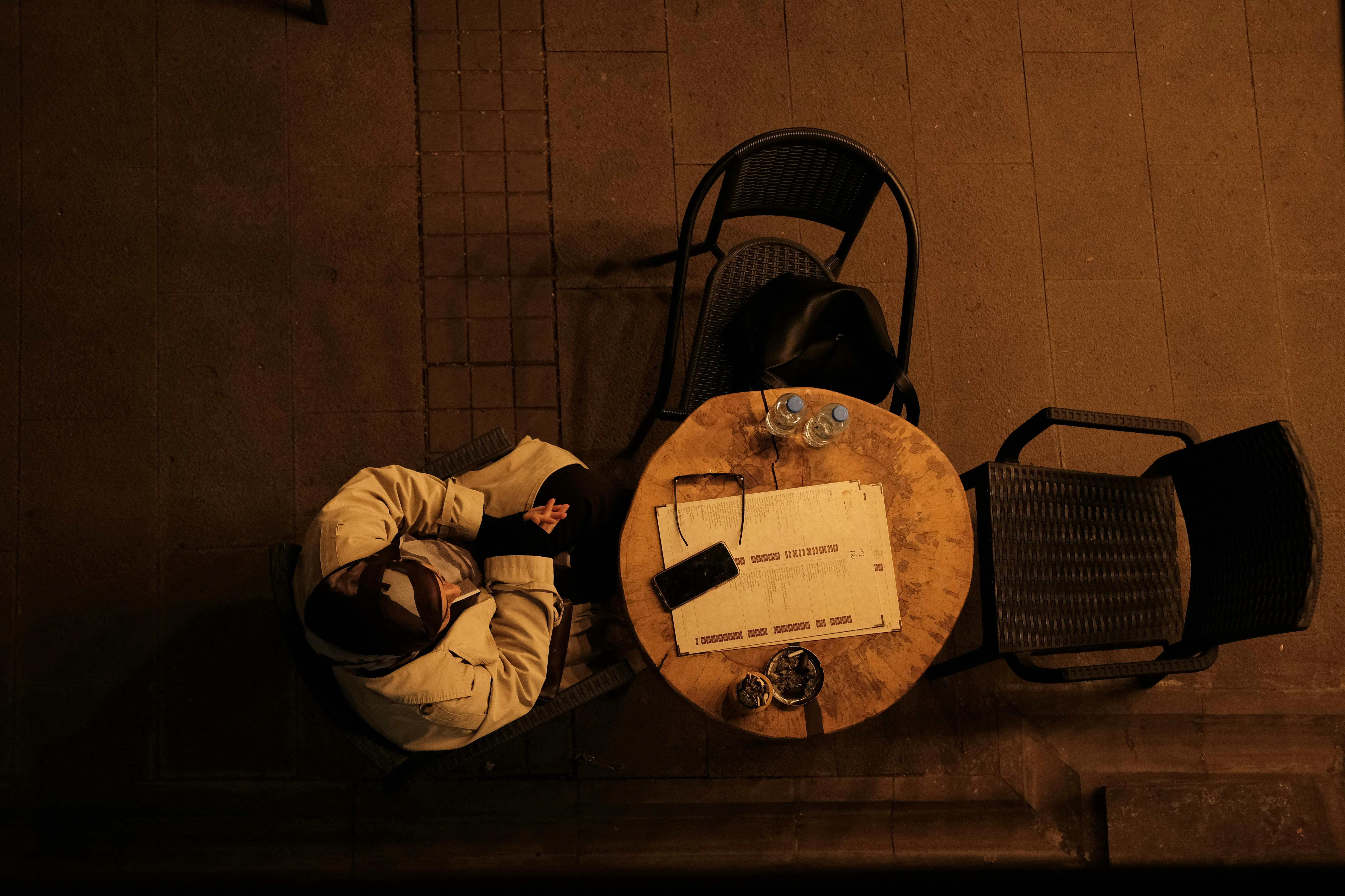 grátis Vista aérea de uma pessoa em uma mesa de café à noite, em um ambiente aconchegante e intimista. Foto profissional