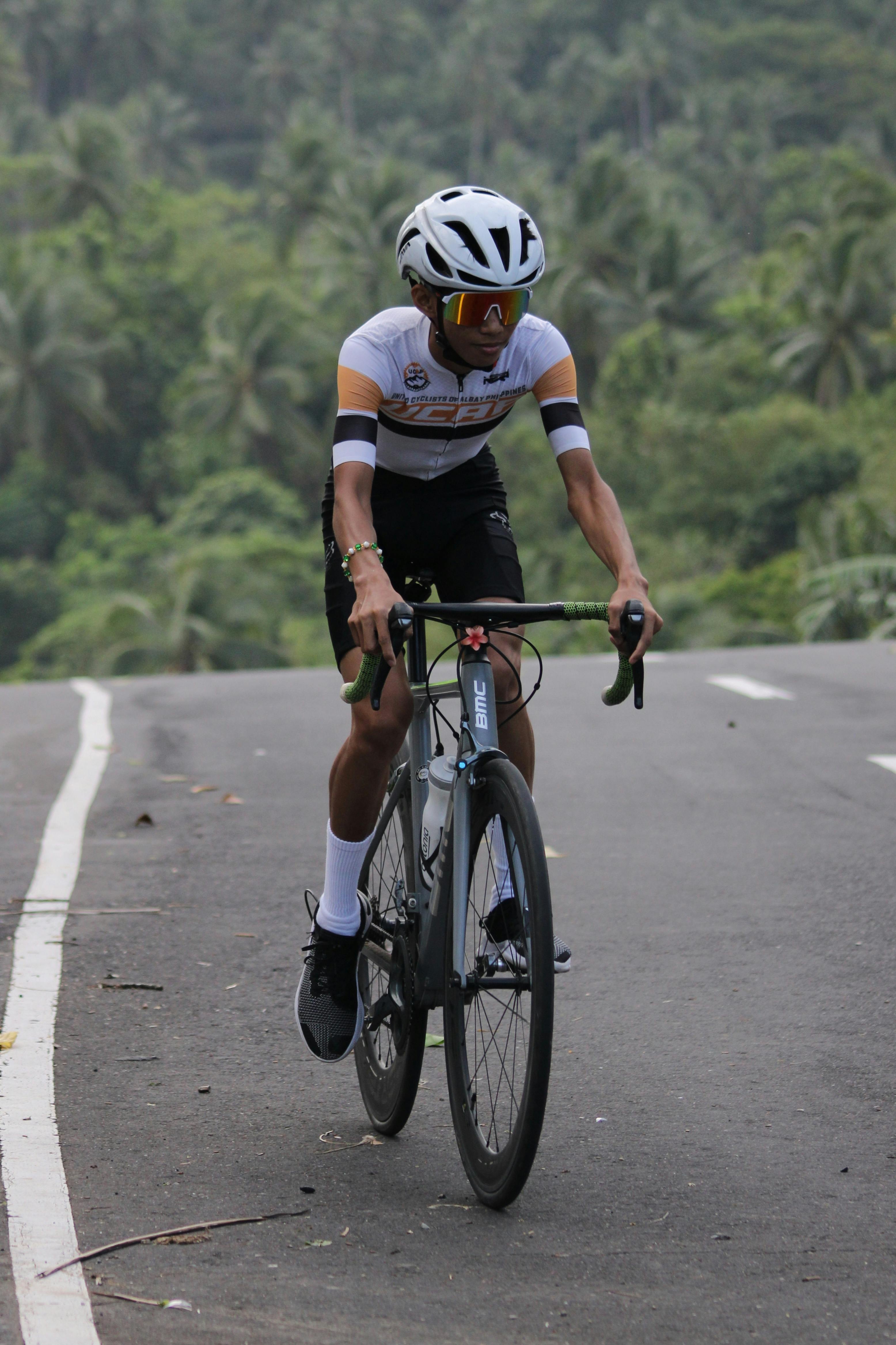 A cyclist descends a winding road through lush greenery, showcasing athleticism and focus.