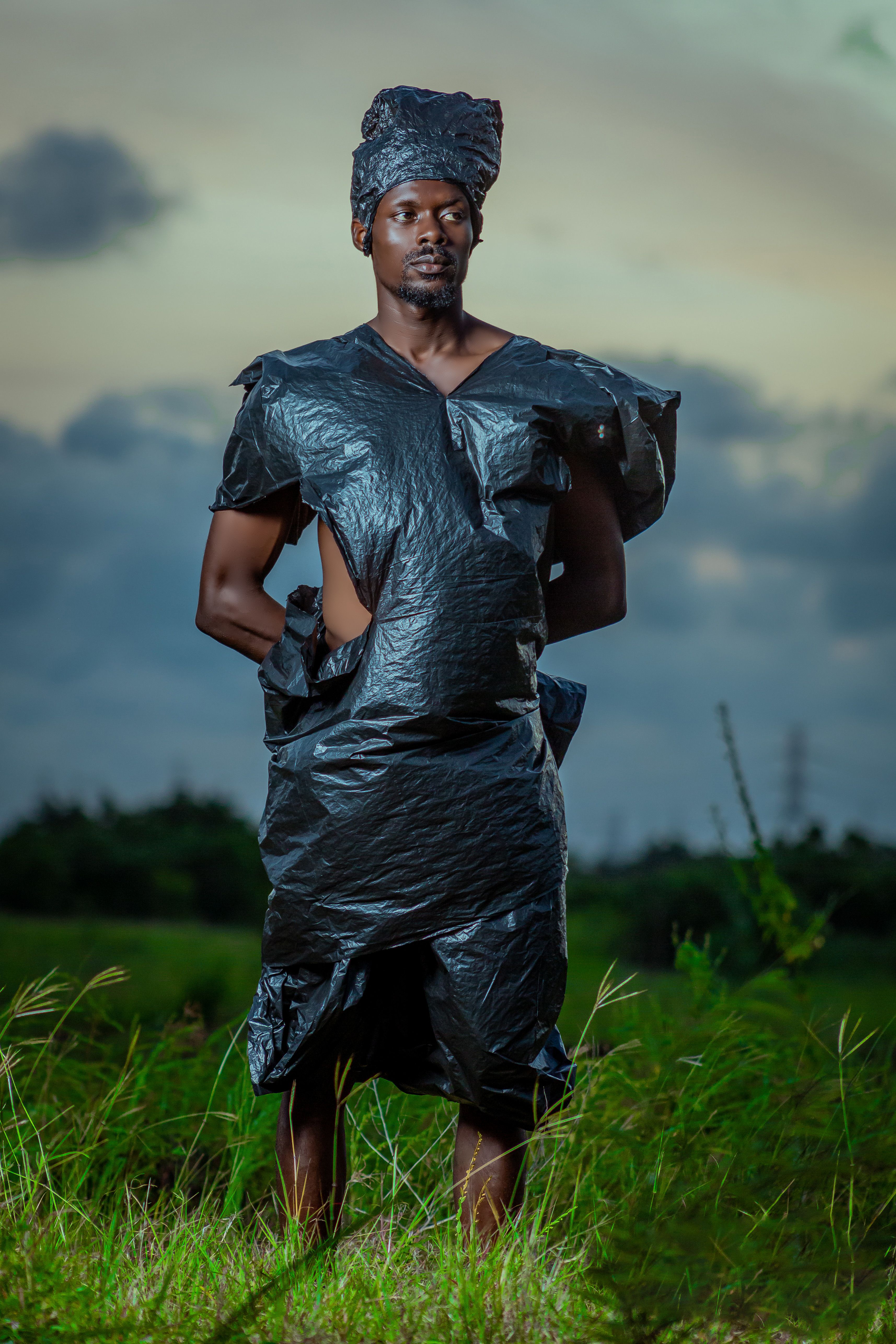 Artistic portrait of a man in a unique black outfit outdoors at sunset.