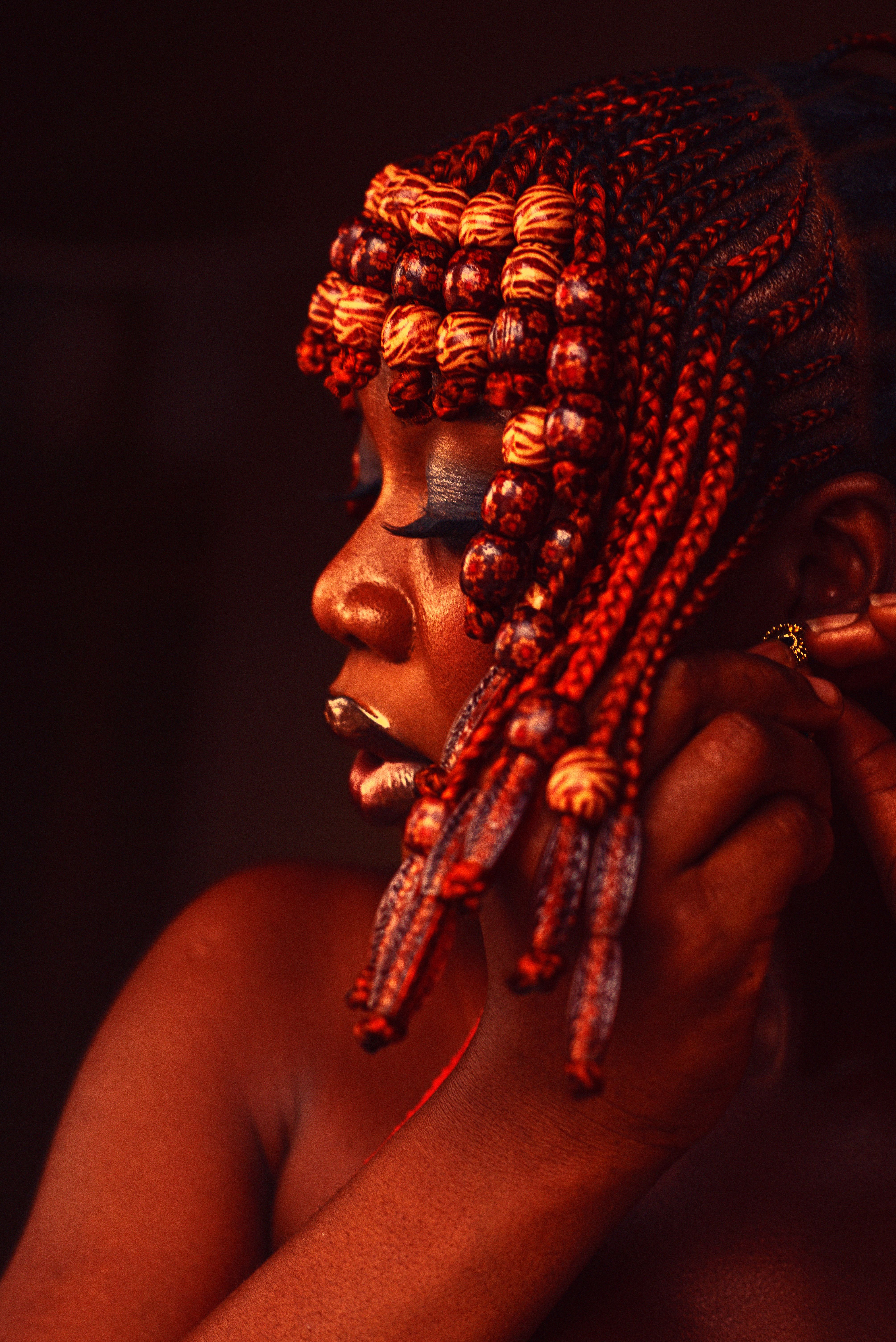 Striking portrait of a woman with intricate, colorful braided hairstyle.